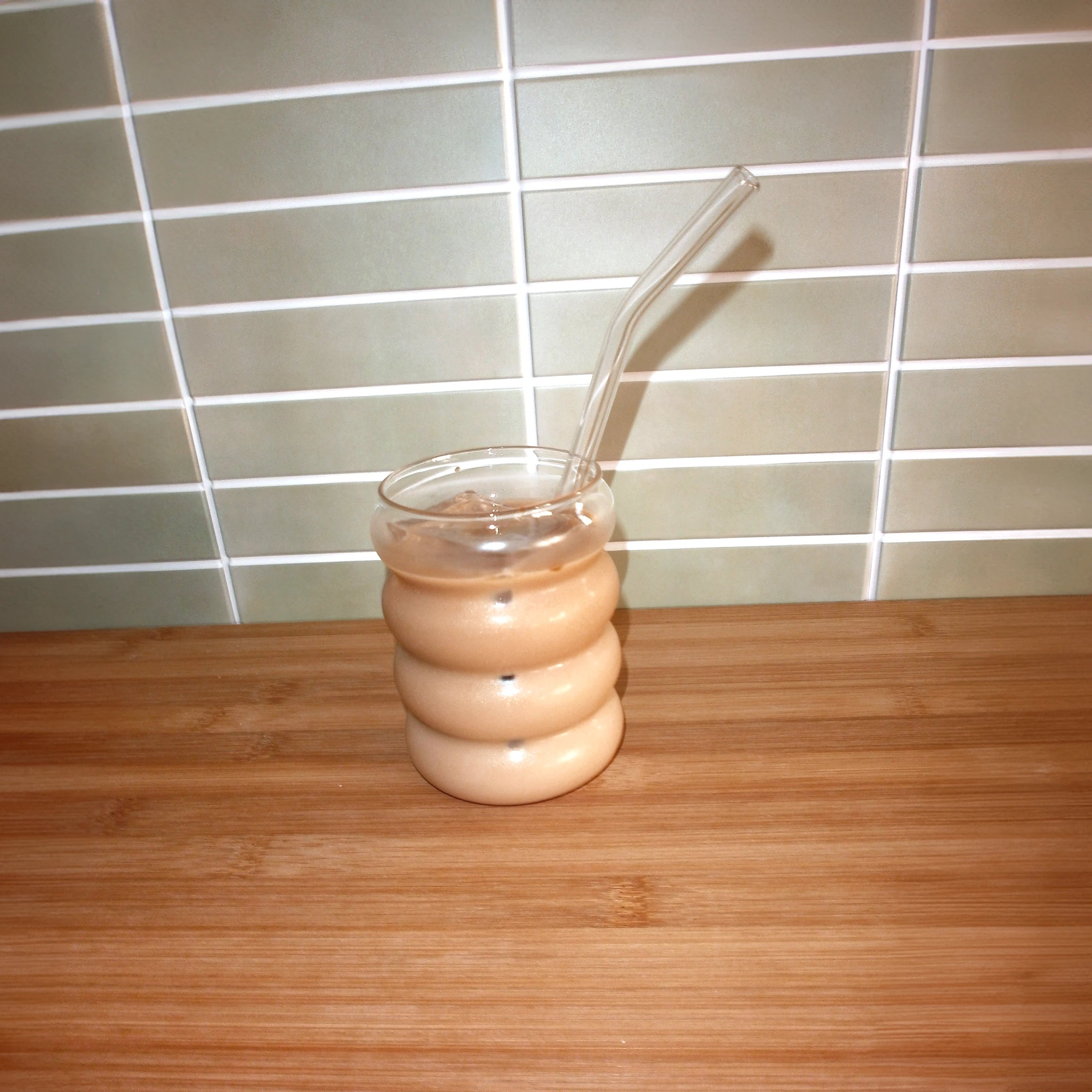 an image of a glass with a glass straw. The glass has homemade iced latte made with Ratio Cold Brew Coffee Concentrate.